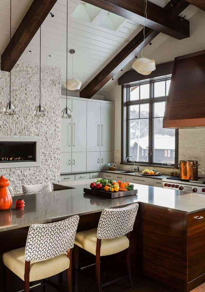 Burası bir kayak evi, oldukça modern tasarımlı şömineli bir mutfak, duvarda parçalanmış mermerle doku oluşturulmuş.