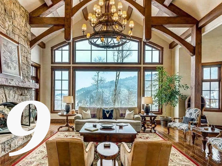 Bu oturma odası dağ manzarasını izleyen uzun cam pencerelerden gelen doğal ışıklarla aydınlanmış, devasa doğal rustik görüntülü kirişlerle oldukça ihtişamlı görünüyor.